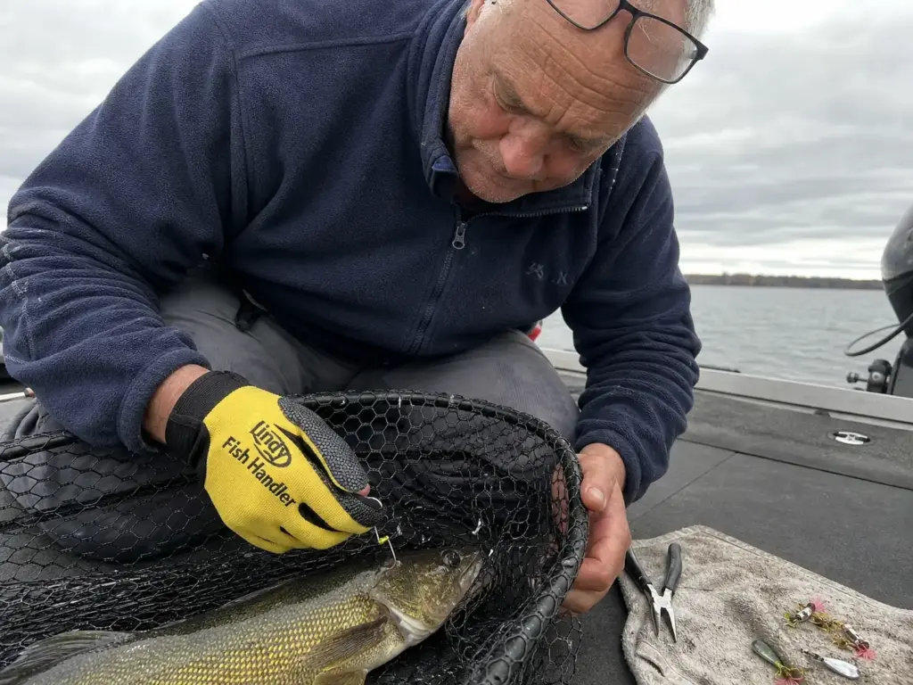Gloved hand unhooking a fish from a mesh net as a real-world glove fit test