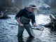 Why Most Fish Stocking Programs Quietly Fail Conservation biologist examining a stressed fish after a fish stocking program release in a cold river