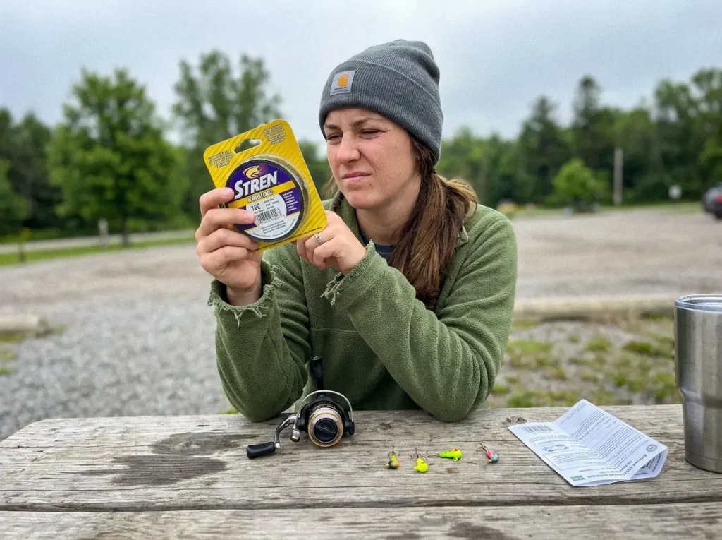 Beginner checking the pound test label on a monofilament spool next to a small spinning reel
