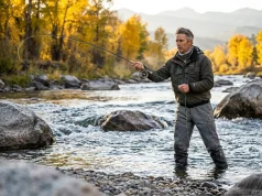 How to Catch Brown Trout in Rivers That Outsmart You Fly angler casting on a fast boulder-strewn river for brown trout at golden hour