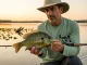 What Most Anglers Miss About Redear Sunfish Angler holding trophy redear sunfish showing the red ear flap margin over a calm freshwater lake