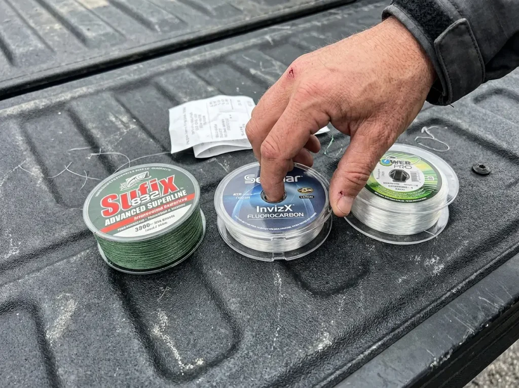 Three types of fishing line spools — braid, fluorocarbon, and monofilament — laid out for comparison