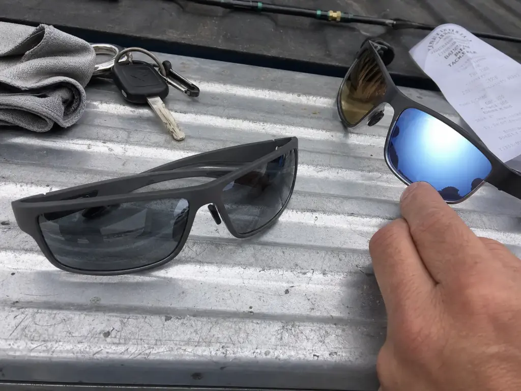 Close-up of polarized fishing sunglasses showing the mirror coating over the darker base tint