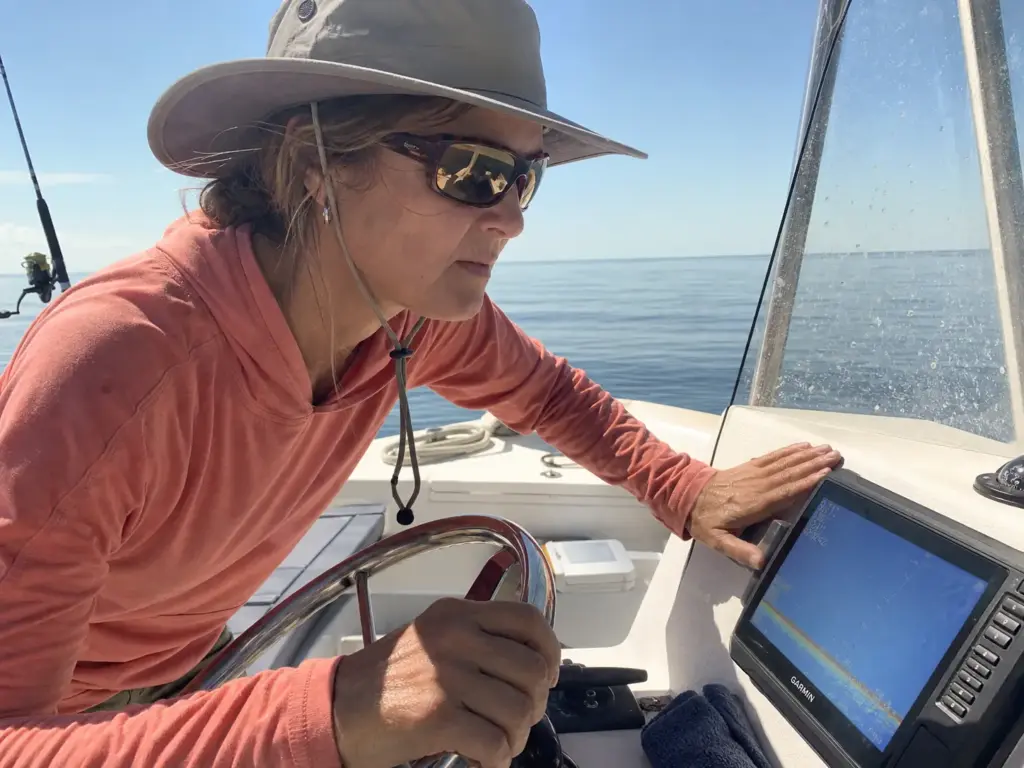 Angler in polarized sunglasses reading a fish finder screen in bright sun on open water