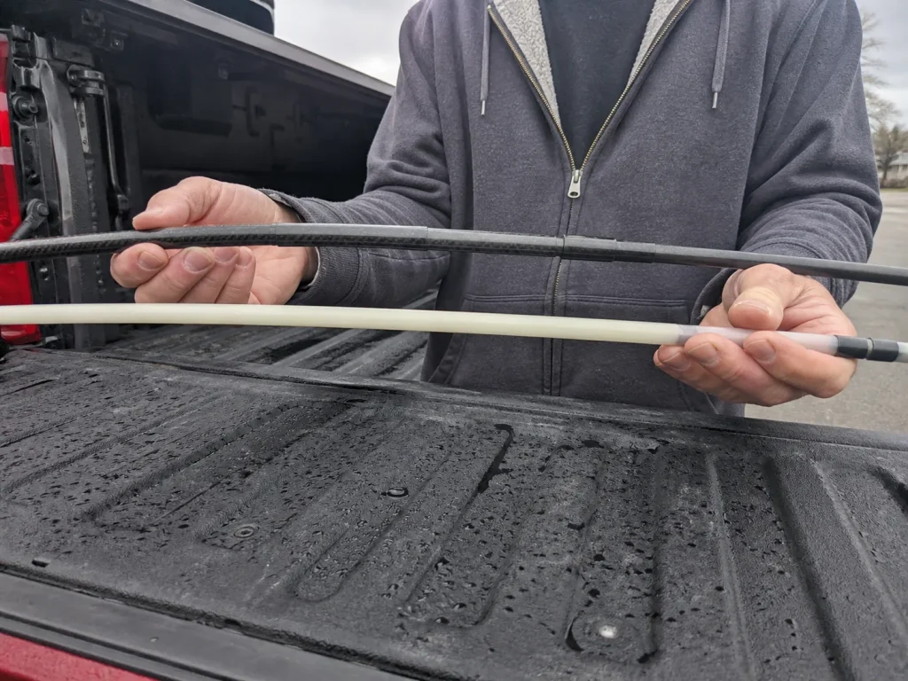 Close-up of a PLUSINNO carbon fiber telescopic rod blank being flexed to show the material