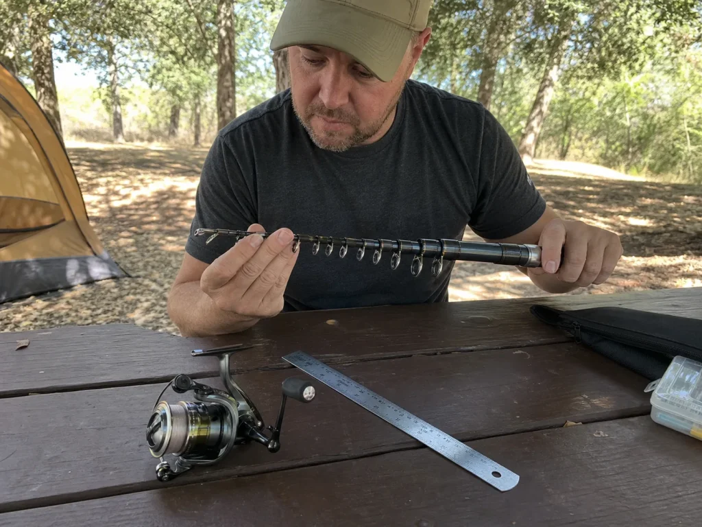 An angler inspecting a telescoping fishing rod's collapsed length and guides before buying