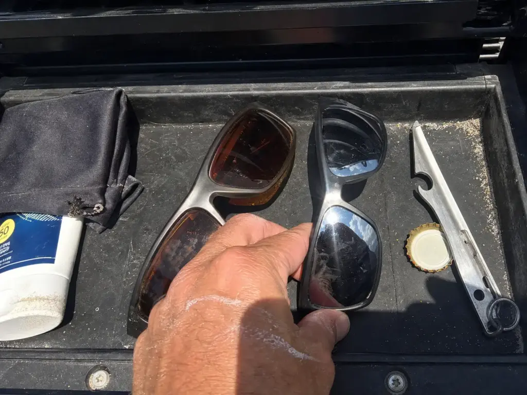 Two pairs of fishing sunglasses in a boat console tray for swapping lens colors during the day