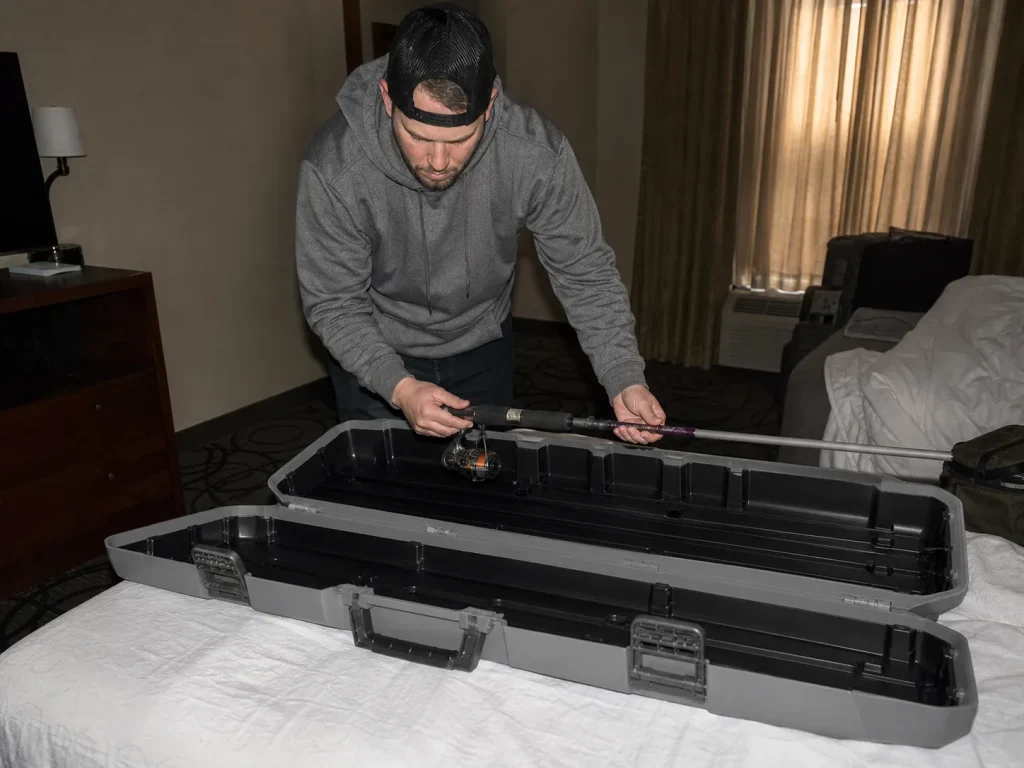 Packing a telescoping fishing rod into a Plano Airliner hard case in a hotel room before a flight