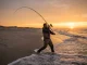 How to Pendulum Cast for Maximum Surf Fishing Distance Surf angler executing a full pendulum cast on a barrier island beach at dawn with a 13-foot rod bent in a full power arc