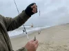 The Second Hook That Changed How I Fish Everywhere Angler's hands holding a finished high-low two-hook surf rig with dropper loops and baited hooks ready to cast at the surf line