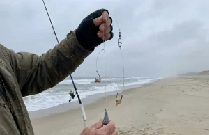 The Second Hook That Changed How I Fish Everywhere Angler's hands holding a finished high-low two-hook surf rig with dropper loops and baited hooks ready to cast at the surf line