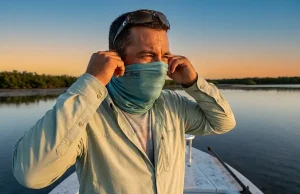 Best Fishing Buff Neck Gaiter for Sun Protection 2026 Angler adjusting a BUFF CoolNet UV neck gaiter on a Florida Keys flats skiff at golden hour