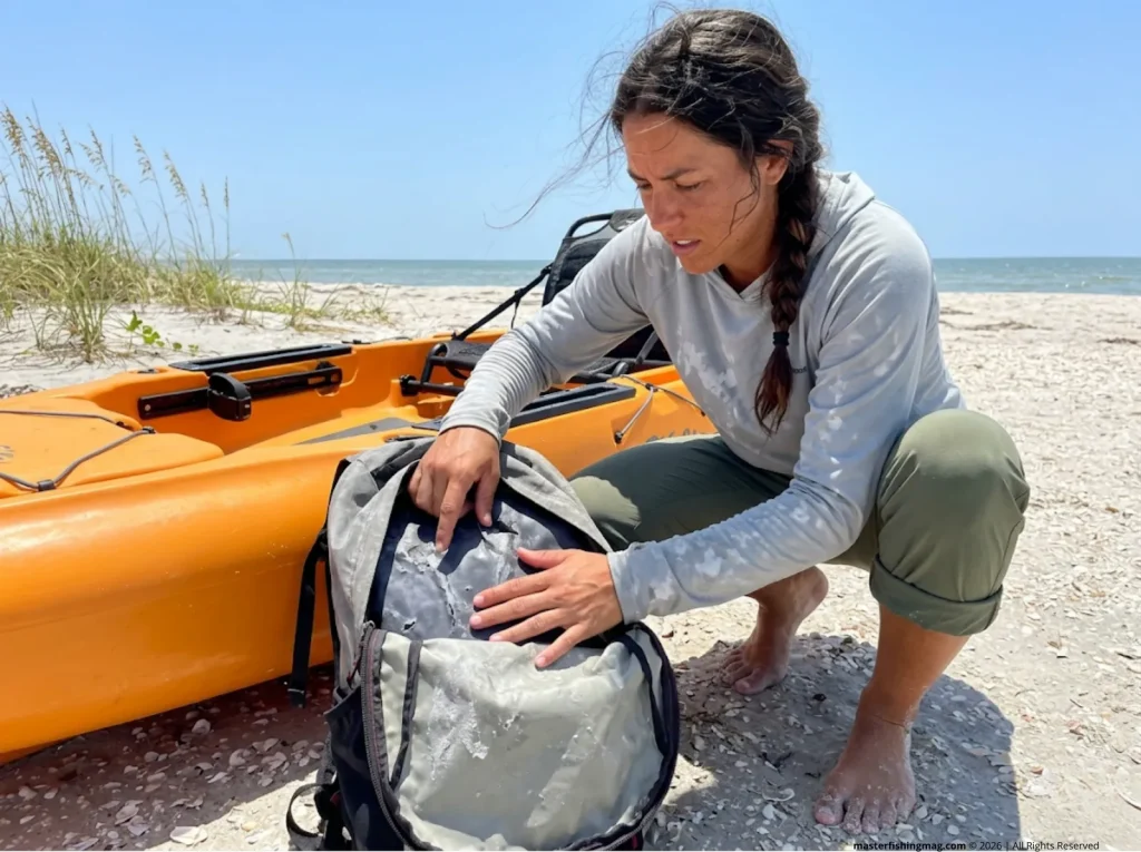 Angler inspecting a degraded and sticky polyurethane interior of a faded grey fishing backpack.