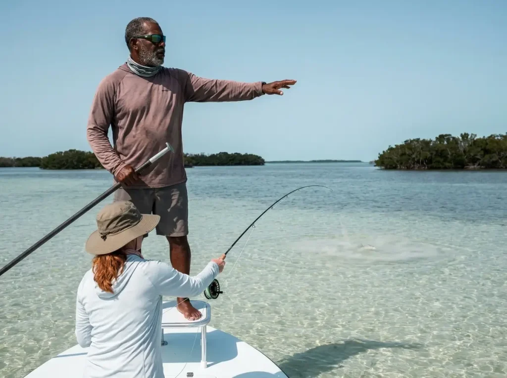 Florida Keys bonefish guide on poling platform directing female angler toward fish on Islamorada flat