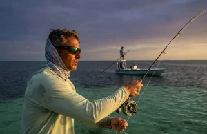 Florida Keys Bonefishing What Most Guides Won’t Say Fly angler mid-cast on a Florida Keys flat at dawn with a flats skiff and guide visible in the background