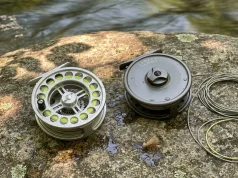 Click Pawl vs Disc Drag Fly Reel What Really Wins Hardy click-pawl fly reel and Lamson disc drag fly reel side by side on streamside rock