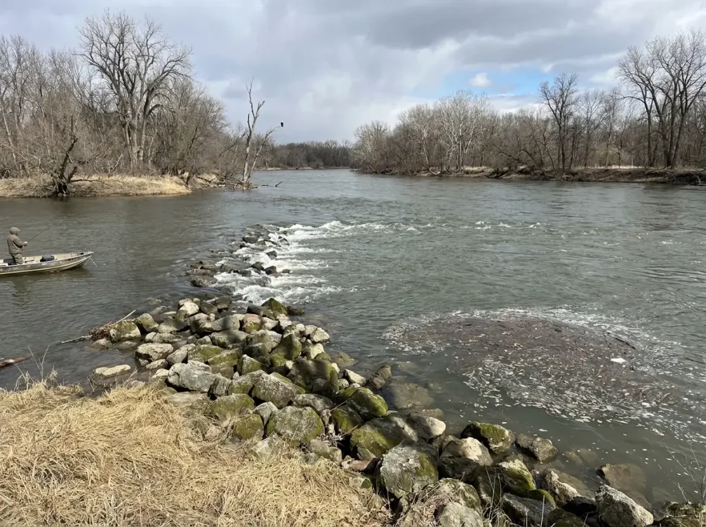 River current breaking around submerged wing dam with walleye staging water visible