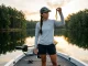 How to Pick Soft Plastic Colors by Water Clarity Angler inspecting soft plastic color selection against sunlight for water clarity.