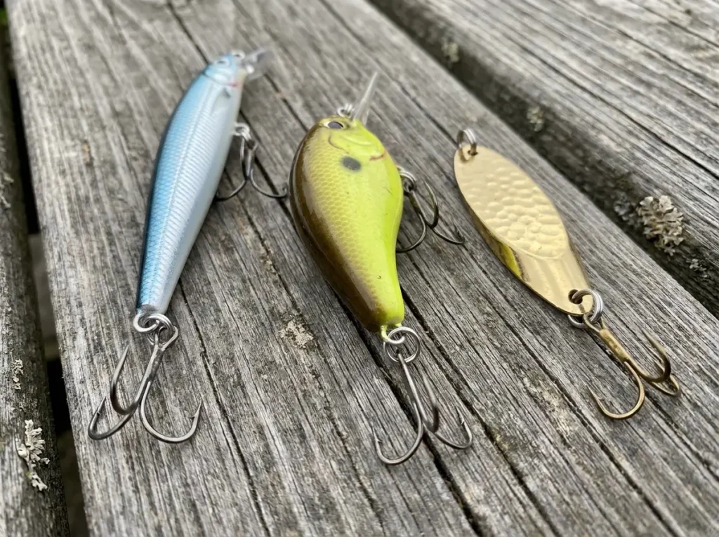 Three fishing lures showing split rings at hook attachment points on wooden dock