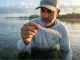 Why Treble Hooks Rust and the Chemistry Fix Angler standing in a saltwater flat inspecting Owner ST-36 treble hooks on a jerkbait for hook rust prevention.
