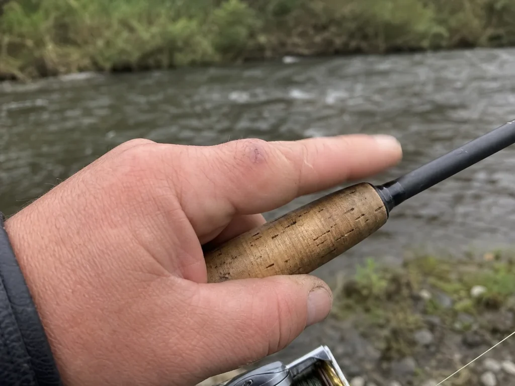 Close-up of an angler's hand gripping a cork rod handle feeling for a bite, cork vs EVA sensitivity