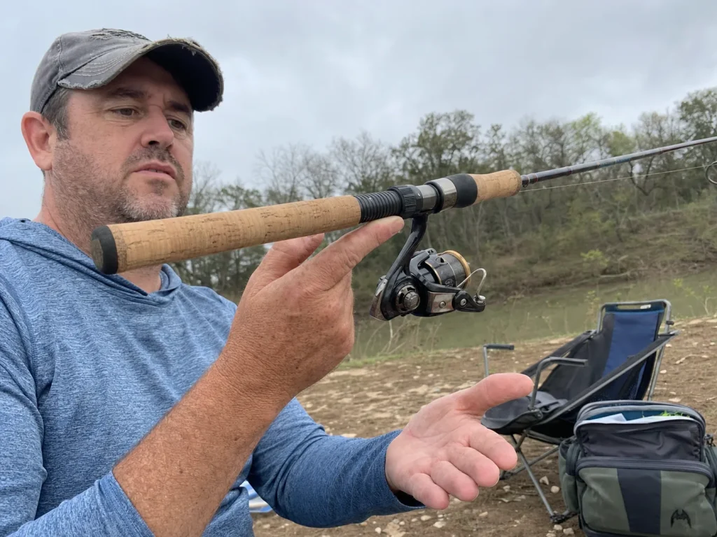 Angler balancing a rod on one finger at the reel seat to show how handle weight affects rod balance