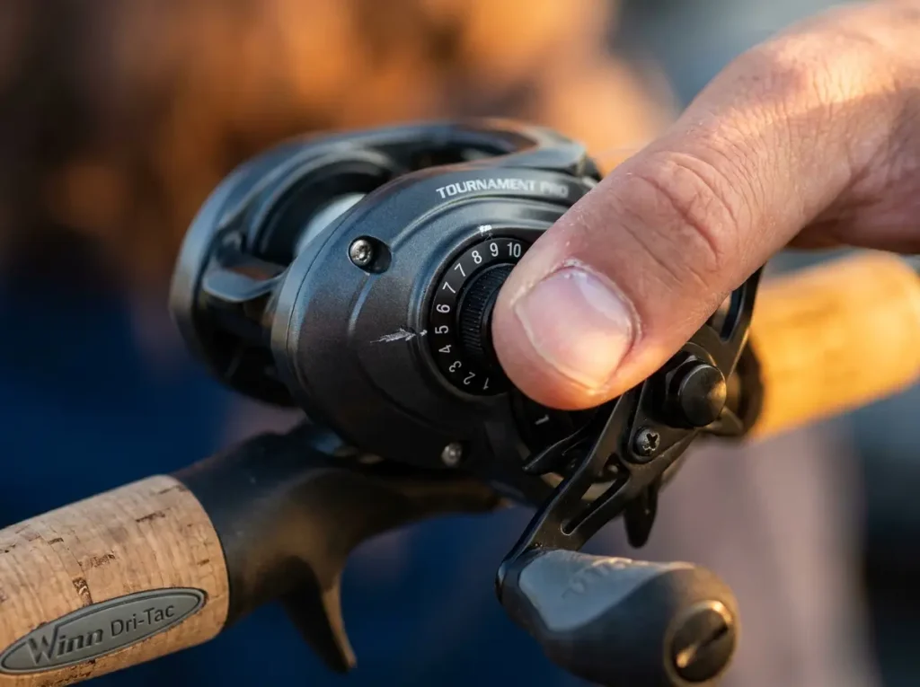 Close-up of baitcaster magnetic brake dial being adjusted for backlash prevention
