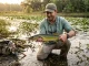 7 Chain Pickerel Facts Most Anglers Get Wrong Chain pickerel held horizontally showing chain-link markings near lily pads