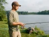 Why Your First Reel Isn’t Always a Spinning Reel Beginner angler holding a spinning combo at a lake, choosing a first fishing reel type