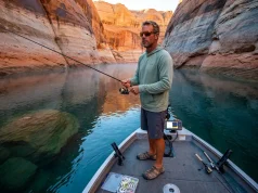5 Fishing Lake Powell Mistakes Costing You Fish Angler casting from a bass boat on Lake Powell with red sandstone canyon walls