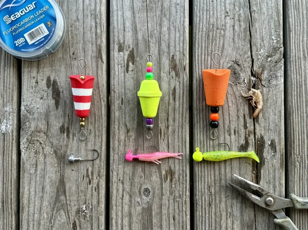 Three different popping cork styles laid out on weathered dock wood with tackle