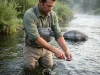 Wading Tool Retractor Guide to What Fails First Wading angler reaching for nippers on a Fishpond retractor clipped to his chest pack in a river