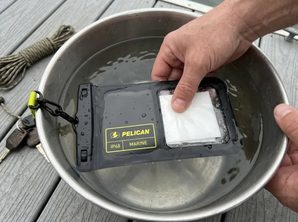 Empty Pelican waterproof phone pouch dunked in a bucket with a dry tissue for a seal test