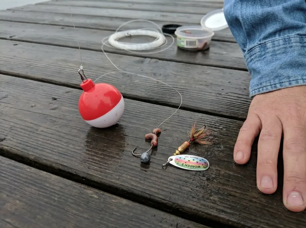 An inline spinner and a tied bobber rig on a wet dock — a beginner's first fishing rig