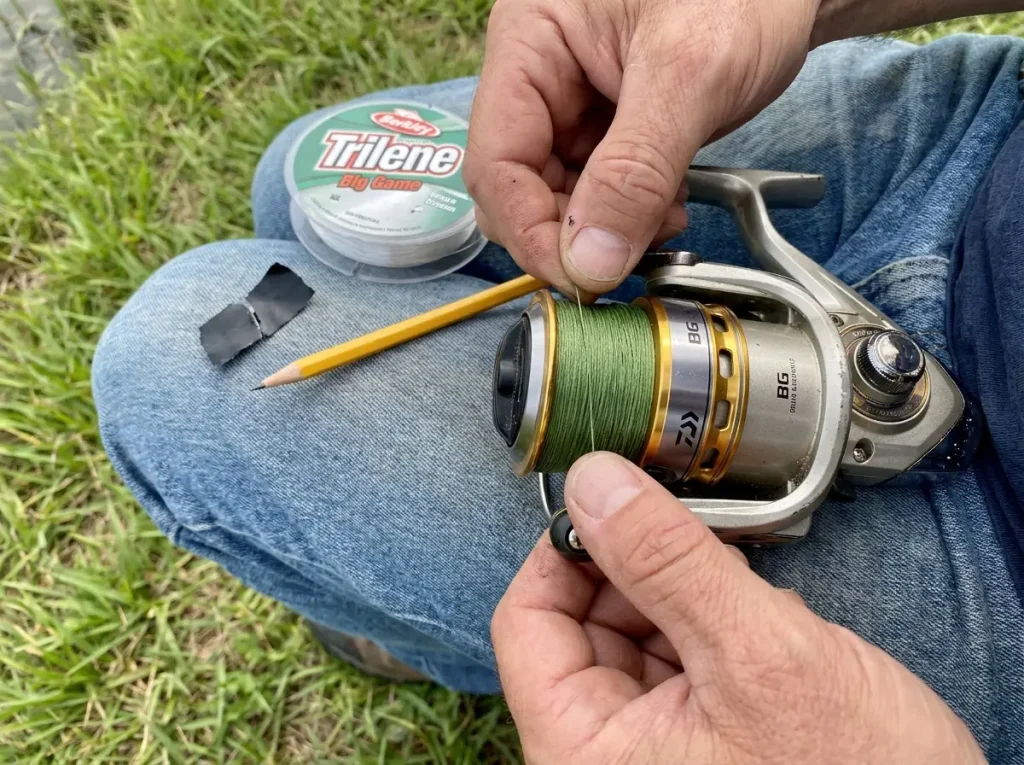 Spooling braided line over monofilament backing onto a spinning reel to stop slip and wind knots