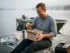 Best Fishing Gifts Anglers Actually Use in 2026 Angler unwrapping fishing gifts on a dock including KastKing polarized sunglasses and a tackle bag