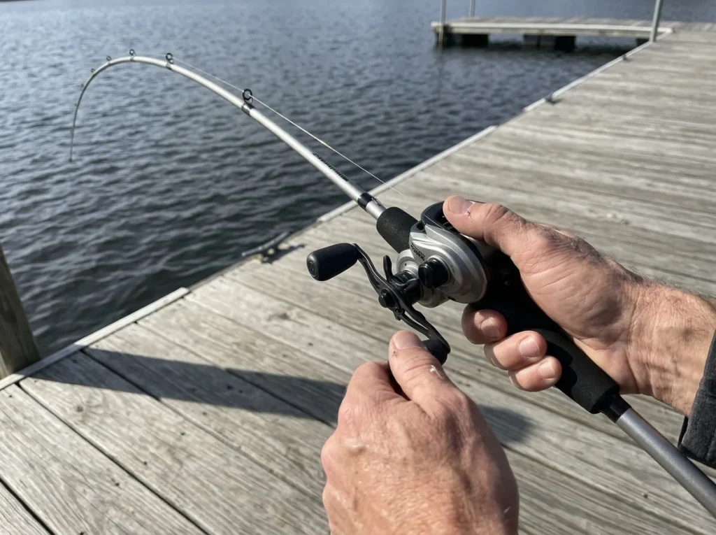 Hands flexing a baitcasting rod under load showing where the fishing rod blank bends