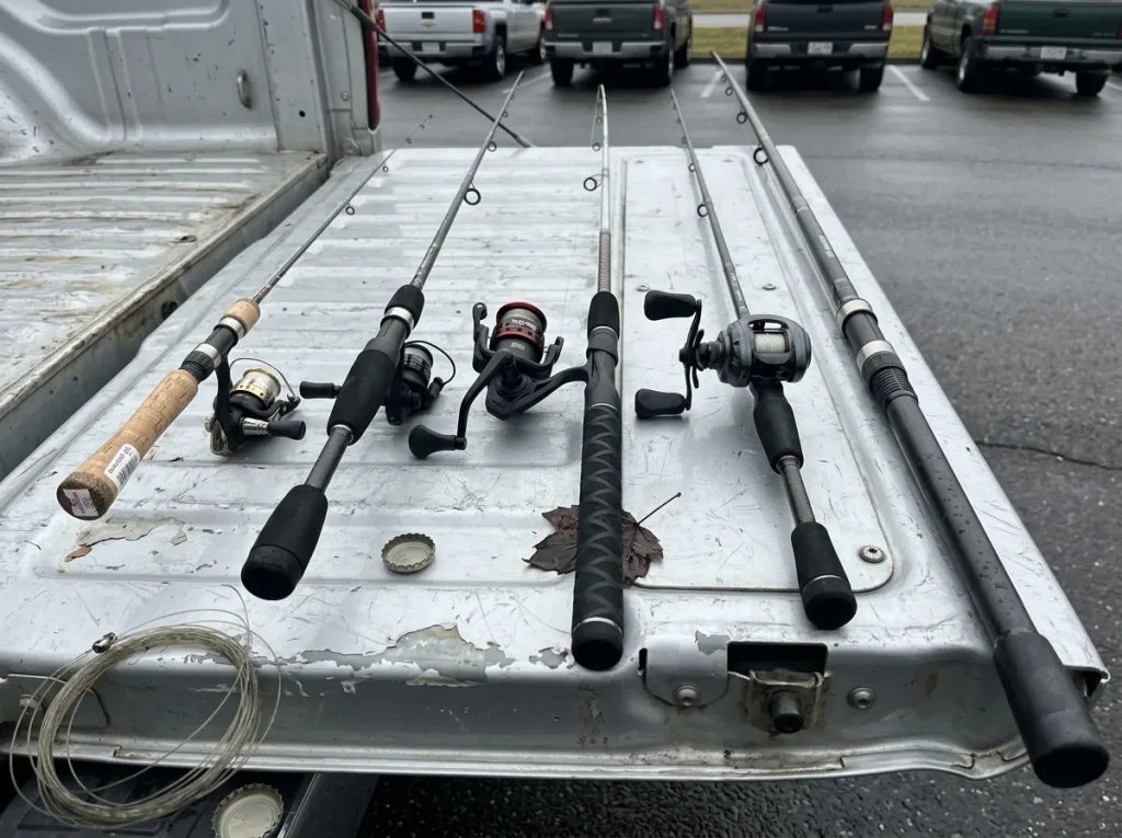 Several different fishing rod types laid out on a truck tailgate showing spinning casting and surf rods