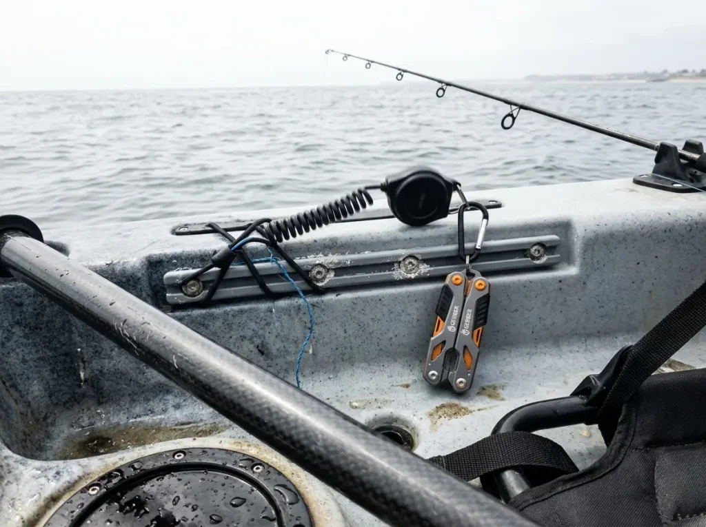 Kayak angler's fishing multi-tool clipped to a retractor within one-handed reach on the deck