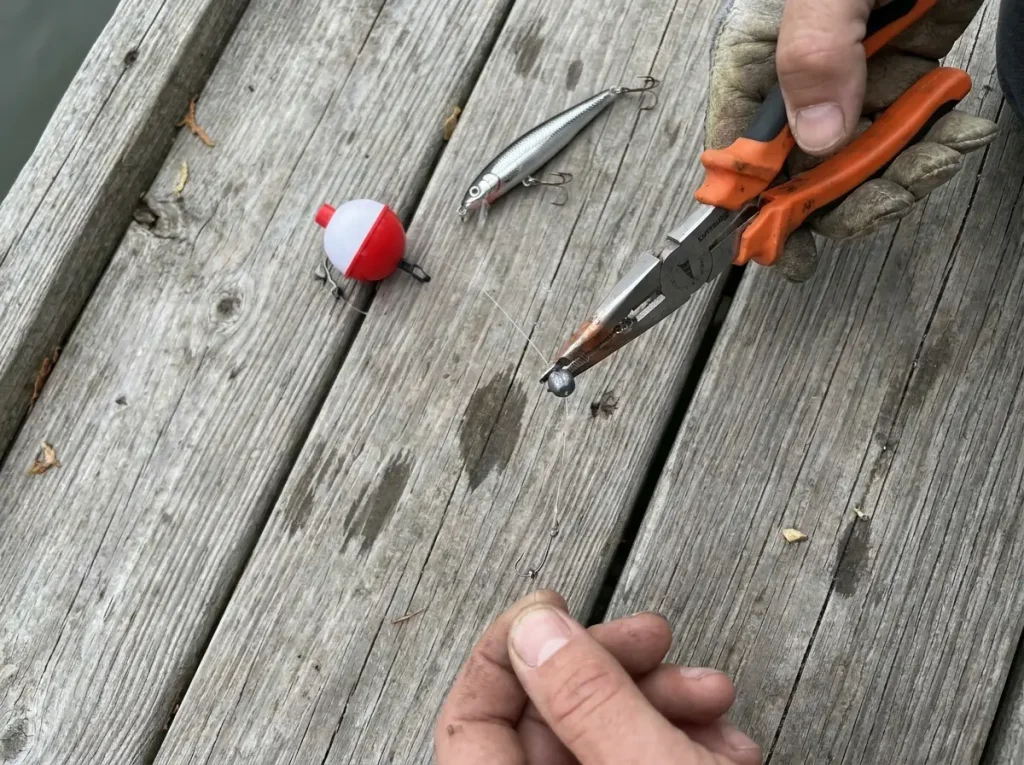 Crimping a split shot onto the line with fishing pliers near a bobber rig