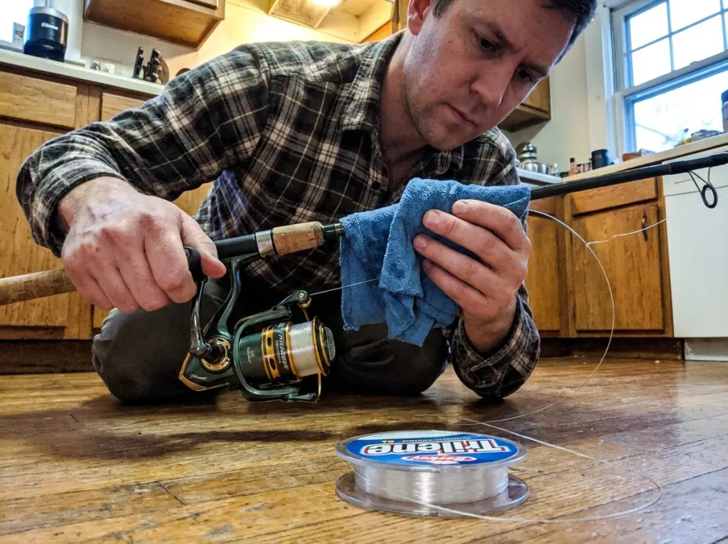 Spooling monofilament onto a spinning reel with a damp cloth for tension