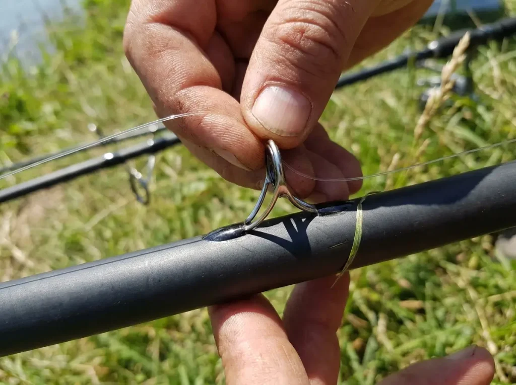 Fishing line being threaded through a rod guide along the blank