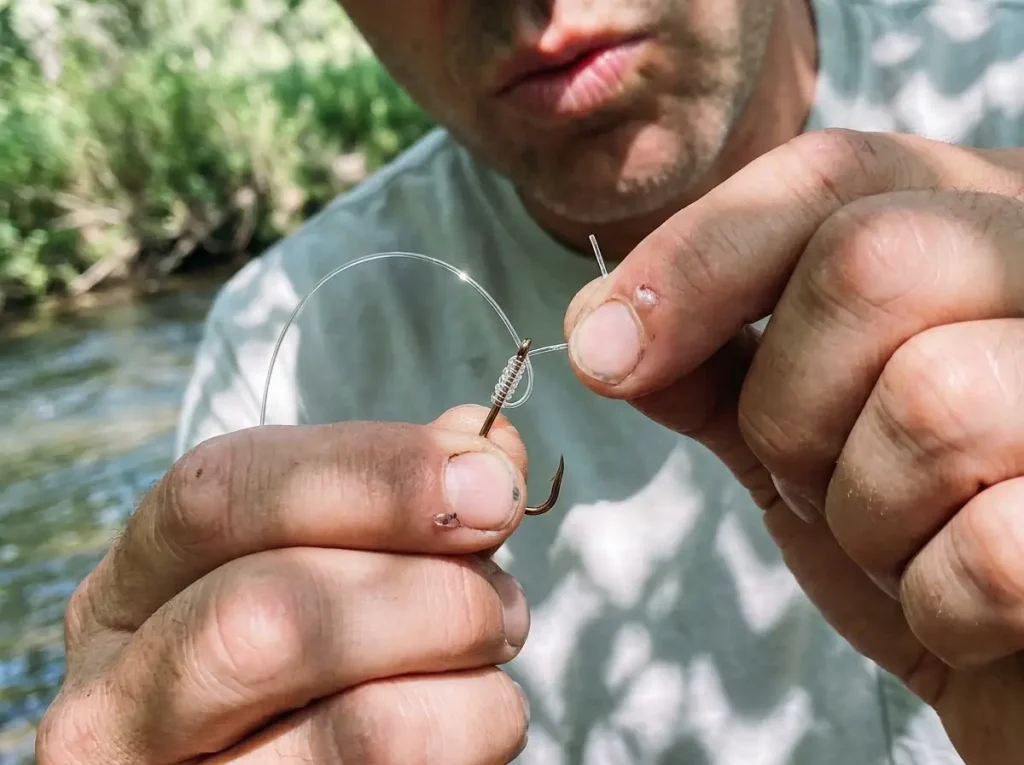 Hands tying an improved clinch knot onto a hook with monofilament