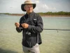 Fishing Apparel and Sun Protection Beyond the UPF Tag Angler in a long-sleeve UPF fishing shirt and wide-brim hat wading shallow water in high sun