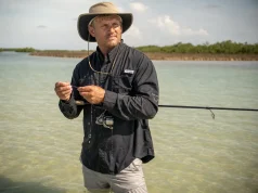 Fishing Apparel and Sun Protection Beyond the UPF Tag Angler in a long-sleeve UPF fishing shirt and wide-brim hat wading shallow water in high sun