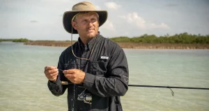 Fishing Apparel and Sun Protection Beyond the UPF Tag Angler in a long-sleeve UPF fishing shirt and wide-brim hat wading shallow water in high sun