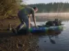 Fishing Kayak Buying Guide What Actually Matters Angler pushing a rigged fishing kayak off a gravel bank at first light