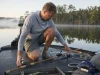 Graphite vs Fiberglass Rods Your Lure Decides Angler choosing between graphite and fiberglass rods laid across a bass boat deck at first light