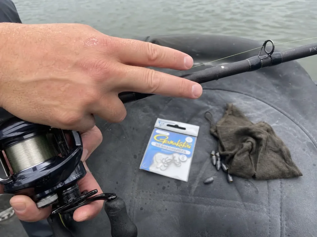 Close-up of fingertips resting on a graphite rod blank to feel a bite, tannin water behind
