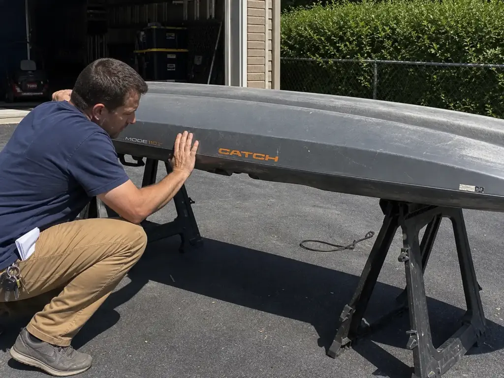 Buyer pressing a used fishing kayak hull to check for soft oil-canning spots